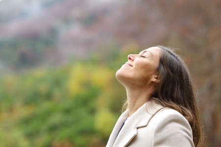 Profile of a satisfied middle aged woman breathing fresh air in a forest in winterの写真素材