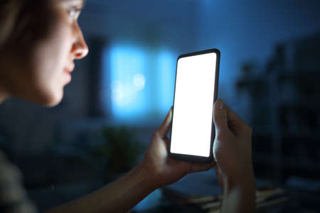 Close up of a woman hand using and showing blank smart phone screen in the night at homeの写真素材
