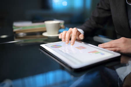 Close up of a tele worker checking online graphs on a tablet late hours at homeofficeの写真素材