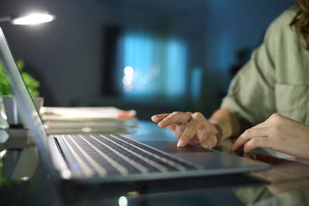 Close up of a woman hand browsing on laptop using touchpad in the night at homeの写真素材
