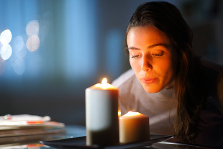 Beautiful woman blowing out candles in the living room at home in the nightの写真素材