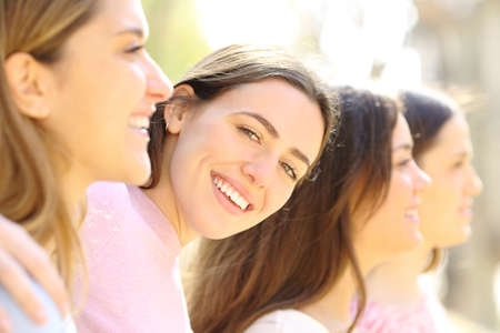 Happy woman with perfect smile posing between her friends in the street a sunny day