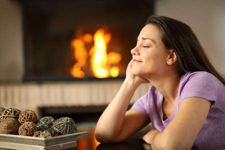 Happy tenant resting beside a fireplace in the living room at homeの写真素材