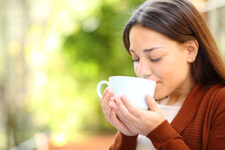 Relaxed woman drinking coffee in a green house gardenの写真素材