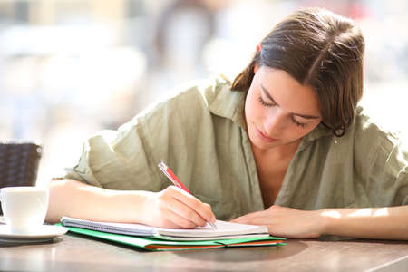 Concentrated student studying taking notes in a notebook in a coffee shop
