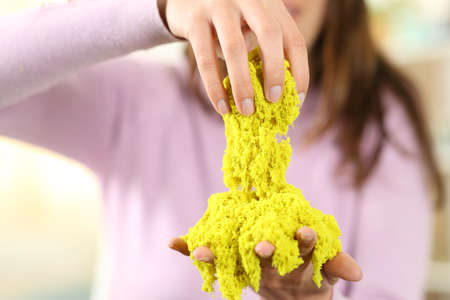 Close up of a woman hands playing with magic cinetic sand at homeの写真素材