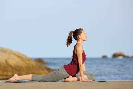 Side view portrait of a yogi doing yoga pose on the beachの写真素材