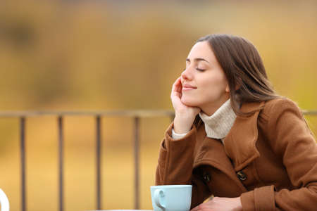Relaxed woman resting with closed eyes sitting in a coffee shop in winterの写真素材