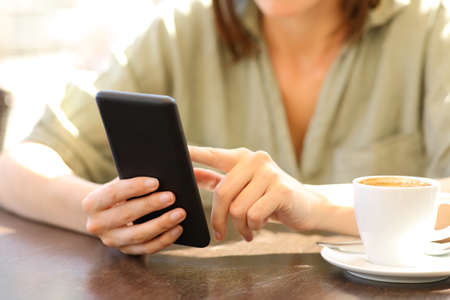 Close up of a woman hands using a smart phone in a coffee shopの写真素材