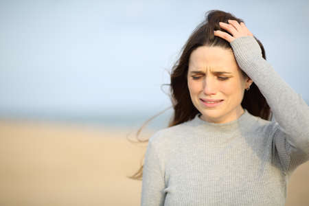 Sad woman walking alone crying on the beachの写真素材