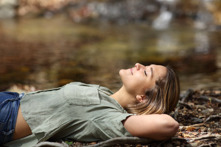 Profile of a happy woman relaxing resting lying in a riversideの写真素材
