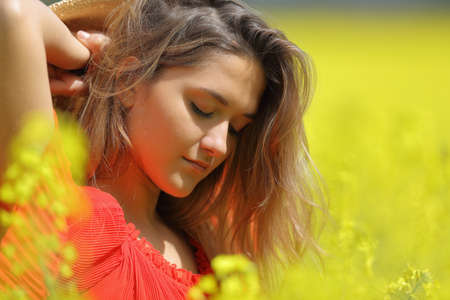 Portrait of a beauty woman in red posing in a yellow flowered fieldの写真素材