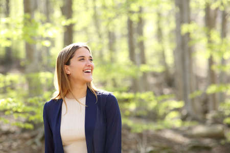 Happy woman contemplating views and laughing in a beautiful forestの写真素材