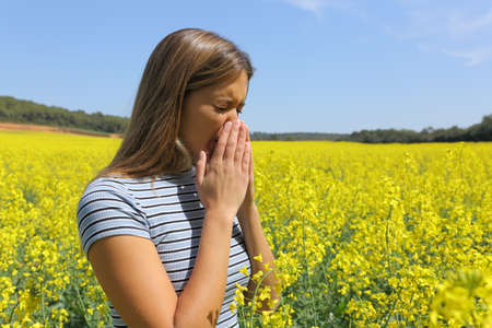 Allergic woman coughing covering mouth with her hands in a yellow fieldの写真素材