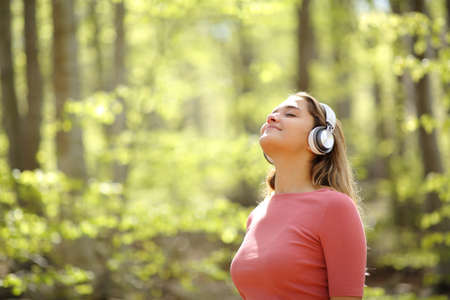 Woman meditating wearing headphones listening audio guide in a forestの写真素材