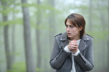 Scared woman walking alone towards camera in a foggy forestの写真素材