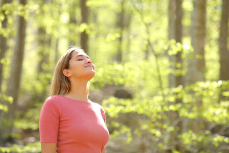 Relaxed woman breathing fresh air in a beauty sunny forestの写真素材