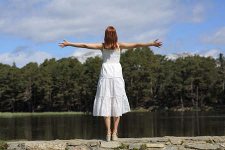 Back view portrait of a woman in white dress celebrating vacation in the mountainの写真素材
