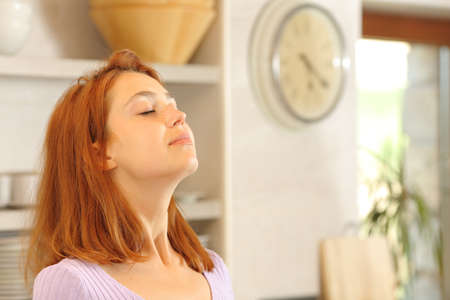 Satisfied woman breathing fresh air in the kitchen at homeの写真素材