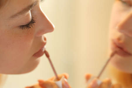 Close up of a serious woman painting lips applying lipstickの写真素材