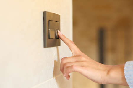 Close up of a woman hand pushing light switch at homeの写真素材