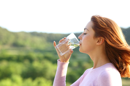 Profile of a woman drinking water from glass outdoor in natureの写真素材