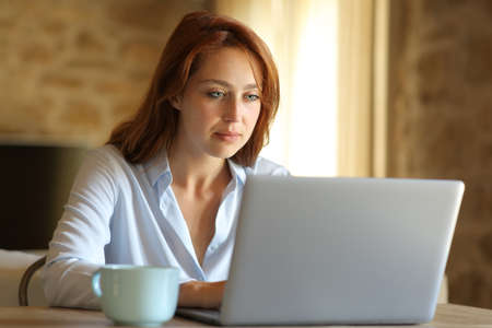Concentrated freelancer woman working with laptop at homeの写真素材