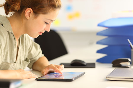 Profile of a woman checking tablet at officeの写真素材