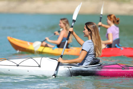 Group of friends rowing in kayaks in a lake on summer vacationの写真素材