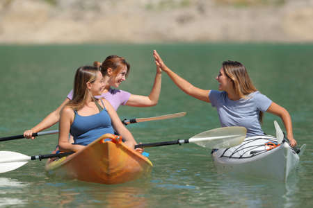 Three friends giving five enjoying a kayak day in a beautiful lake on summer vacationの写真素材