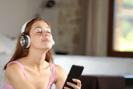 Relaxed homeowner wearing headphones listening to music at homeの写真素材