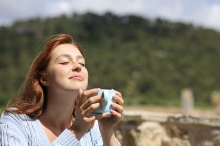 Woman enjoying outdoors holding a coffee cup in the mountain