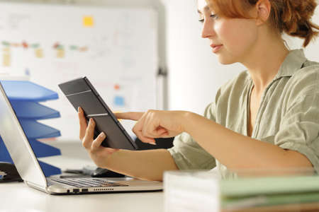 Concentrated woman working at office checking tablet contentの写真素材