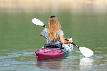 Back view of a woman rowing in a kayak in a beautiful lakeの写真素材
