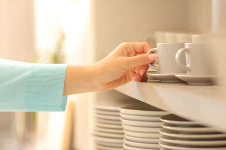 Close up of a woman hand hatching a coffee cup in the kitchenの写真素材