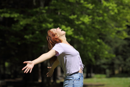 Happy woman screaming to the air outstretching arms in a forestの写真素材