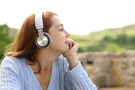 Profile of a woman listening to music on headphones contemplating views outdoorsの写真素材