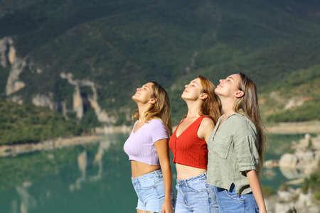 Side view portrait of three friends breathing fresh air in the mountainの写真素材