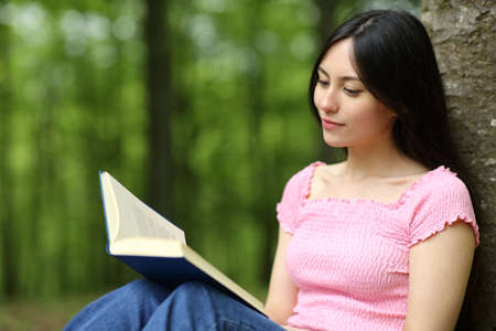 Asian woman reading paper book sitting in a parkの写真素材