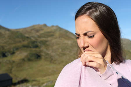 Disgusted woman smelling stinky clothes in the mountainの写真素材
