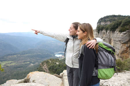 Two happy trekkers standing in the top of a cliff pointing away