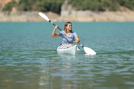 Front view portrait of a happy woman in a kayak rowing in a lakeの写真素材