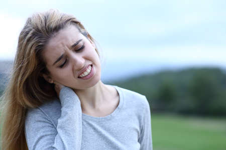 Teen complaining suffering neck ache in a fieldの写真素材
