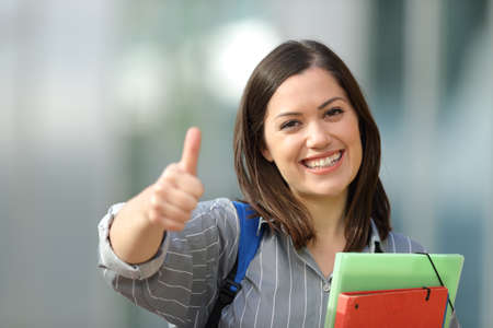 Front view portrait of a happy college student gestures thumbs up lloking at youの写真素材