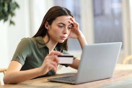 Worried woman having problem buying online with credit card and laptop at homeの写真素材