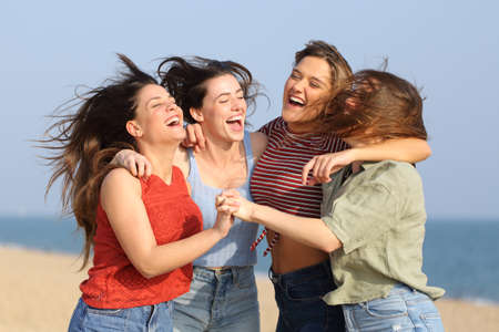 Four excited friends jumping and celebrating vacation on the beachの写真素材