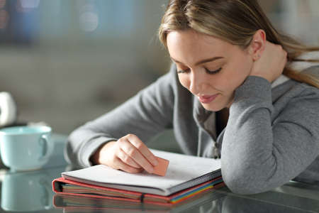 Student erasing text on notebook using eraser at homeの写真素材