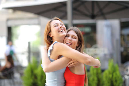 Two funny friends meeting laughing and embracing in the streetの写真素材