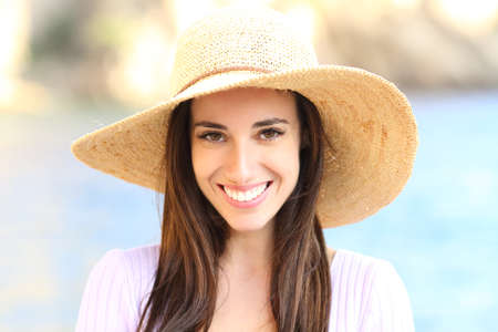Happy woman wearing pamela on the beach looking at camera smiling with perfect teethの写真素材