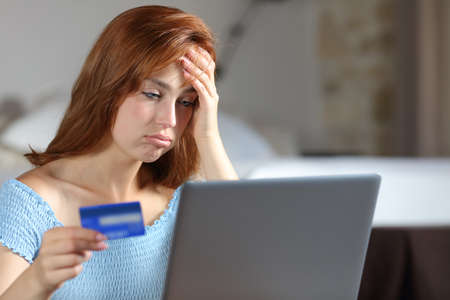 Frustrated woman having problems paying online with credit card and laptop in the bedroomの写真素材